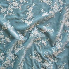 a blue and white flowered fabric with small white flowers on the top of it