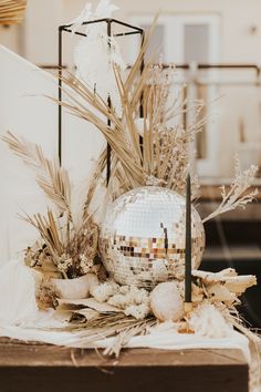 a table topped with a disco ball and plants next to a mirror ball on top of a wooden box