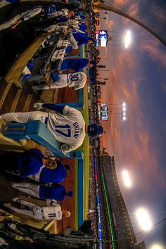 some baseball players are lined up on the sidelines in their dugouts at night