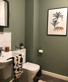 a white toilet sitting next to a bathroom sink under a framed animal print on the wall