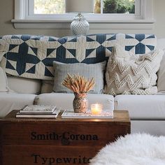 a living room with a white couch and pillows on top of the couch is lit by a candle