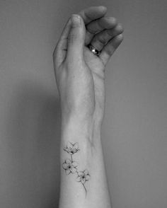 a woman's wrist with a small flower tattoo on the left side of her arm