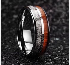 a wedding ring with wood and silver inlays on the inside, sitting on a black background