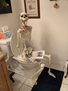 a skeleton sitting on top of a toilet in a bathroom