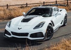 a white sports car is driving down the road in front of mountains and dry grass