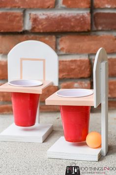 two plastic cups sitting on top of each other next to a basketball hoop and an orange ball