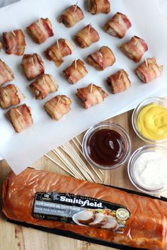 bacon wrapped in strips next to dipping sauces and other ingredients on a cutting board