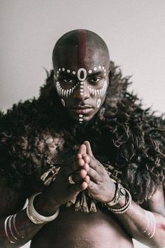 a man with his face painted in white and red, standing next to a wall