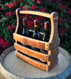 a wooden crate filled with bottles of wine sitting on top of a barrel next to flowers