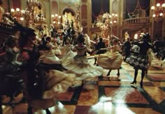 a group of people dressed in costume dancing on a floor with chandeliers and lights