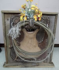 a vase with flowers in it sitting on top of a wooden box filled with rope