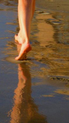 a person walking on the beach with their feet in the water