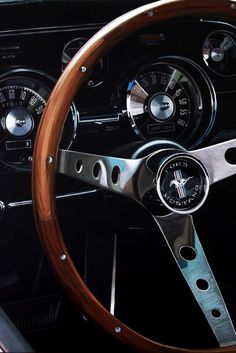 the steering wheel and dashboard of an old classic car with wood grained dash boards