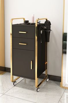 a black and gold cart with two drawers on wheels in front of a white wall