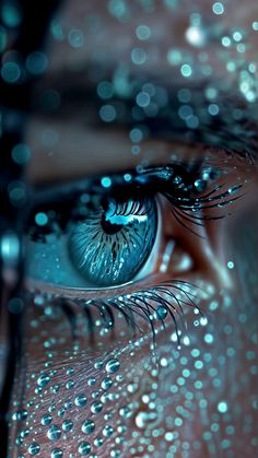 a woman's blue eye with water droplets on the iris and her reflection in it