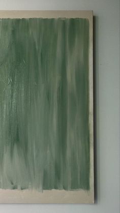 an abstract painting with green and white paint on the wall, in front of a gray background