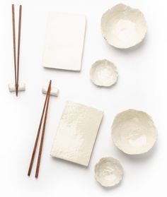 bowls, chopsticks and paper on a white surface