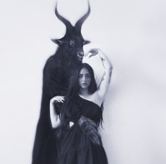 a woman standing next to a demon with long black hair and horns on her head