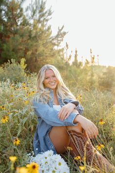 a beautiful blonde woman sitting in the middle of a field full of wildflowers