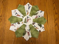 a green and white paper snowflake sitting on top of a wooden table