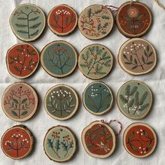 twelve embroidered wooden ornaments are arranged on a table