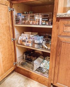 an organized pantry with clear bins and wooden cabinets