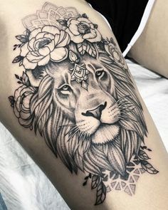 a lion with flowers on its head is shown in black and grey tattoo art work