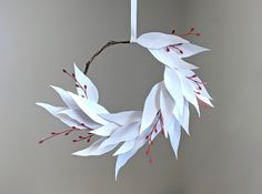 a white paper wreath hanging from a twig