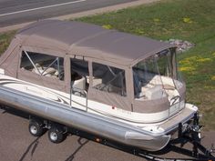 a boat with a cover on it is parked in the parking lot next to some grass