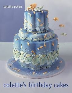 a three tiered blue cake with gold fish on it