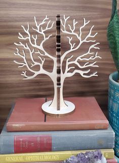 a white tree sculpture sitting on top of a stack of books next to a plant