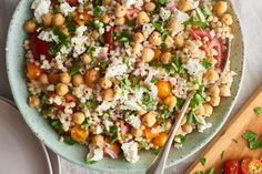 a salad with chickpeas, tomatoes and feta cheese in a blue bowl