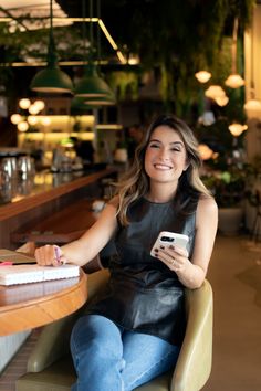 a woman sitting in a chair holding a cell phone