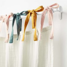 four different colored ties hanging on a curtain rod