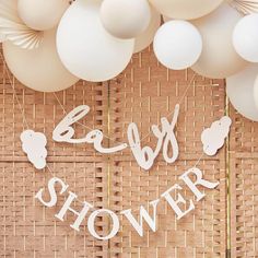 baby shower sign surrounded by white balloons and streamers on a bamboo mat background with paper cutouts