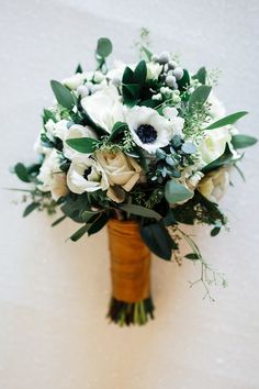 a bridal bouquet with white flowers and greenery