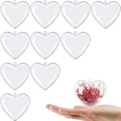 a hand holding a heart shaped object in front of many other hearts on a white background