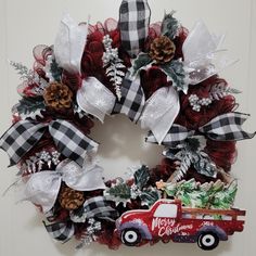 a christmas wreath with a red truck and pine cones