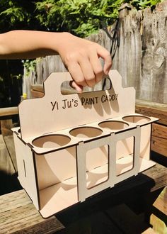 a person holding up a cardboard box with four cupcakes in it that says yi ji's paint caddy