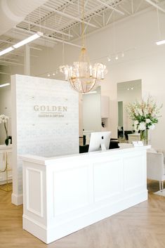 a white reception desk with a chandelier hanging from the ceiling