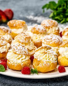 a white plate topped with pastries covered in powdered sugar and raspberries