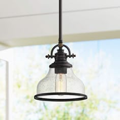 a light fixture hanging from the ceiling in a room with an open window behind it