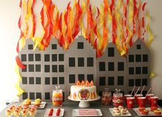 a table topped with cupcakes and desserts next to firetruck decorations