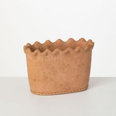 a clay cup with scalloped edges on a white surface