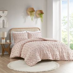 a bed with pink comforter and pillows in a room