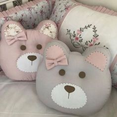 two teddy bears are sitting on pillows in a crib with pink and gray accents