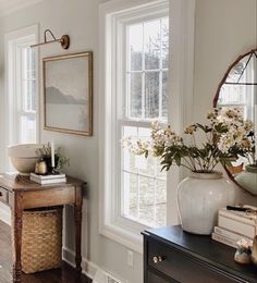 a room with a mirror, table and vase on it's shelf next to a window