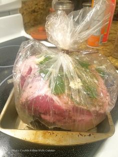 a large piece of meat wrapped in plastic sitting on top of a stove