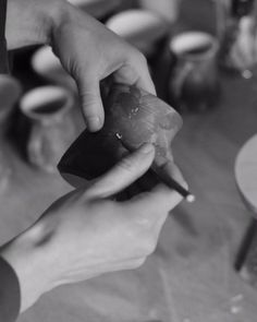 a person holding something in their hand while sitting at a table with other people around