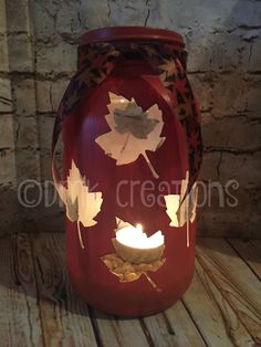 a lit candle in a jar with leaves on it